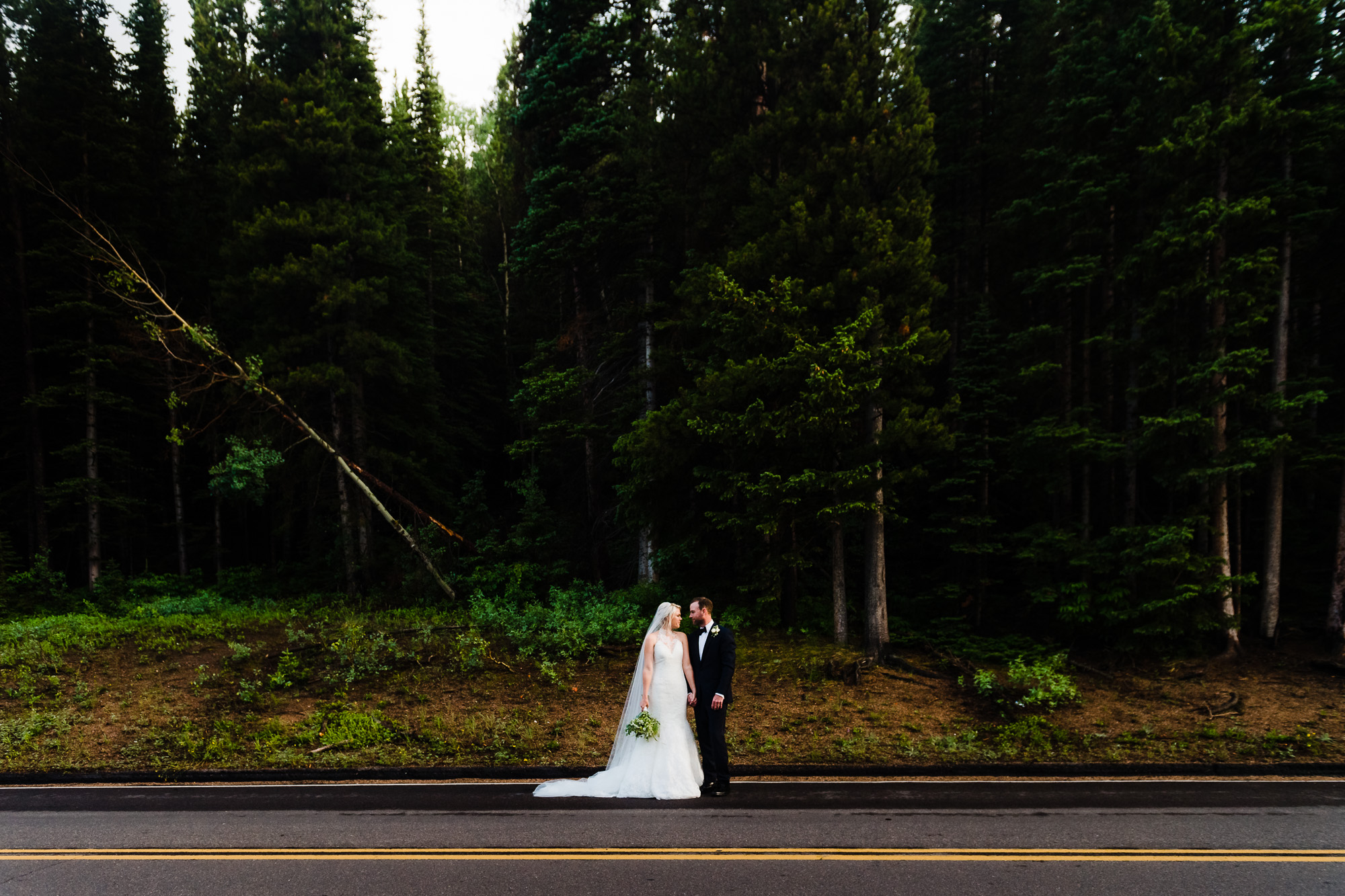 Couple in wedding attire in estes park in front of trees